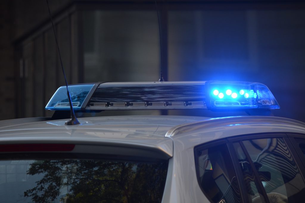 A police car with blue emergency lights flashing on the roof at night.