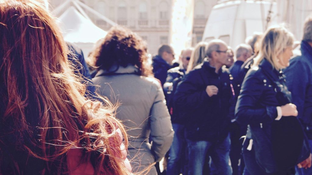 A crowd of people walking outdoors at a public event, seen from behind.